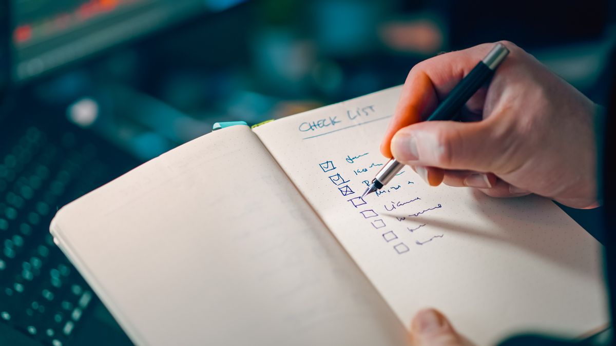 Bàn tay ghi dấu các mục trong sổ checklist — chuẩn bị hồ sơ visa theo từng dòng