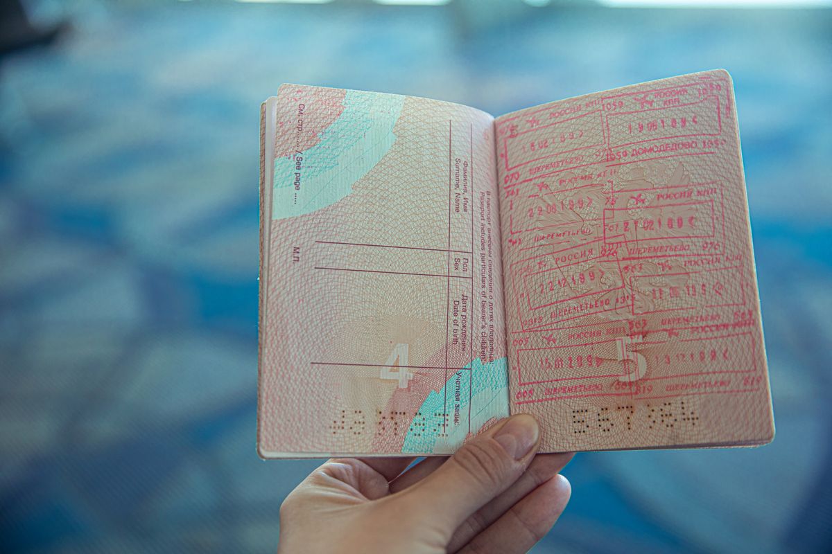Tay cầm hộ chiếu mở — phần bảo hiểm trong hồ sơ visa bị đối chiếu từng dòng